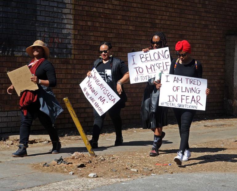 A picture of South African women walking whilst holding posters against GBV.