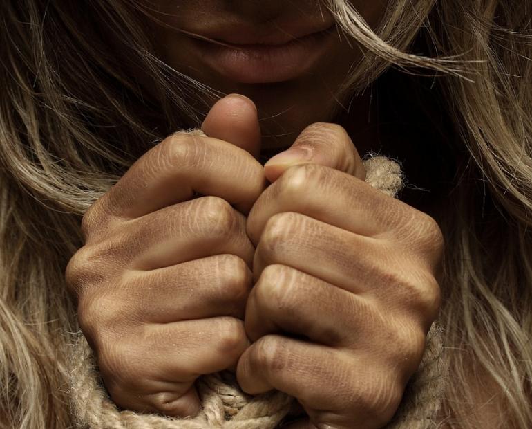 Woman’s hands tied together with a rope 