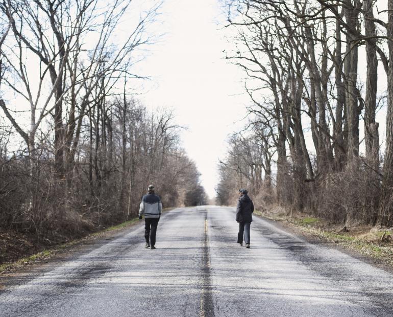 Two people walking on the empty road