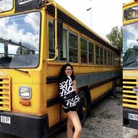 A gril smiling in front of an school bus