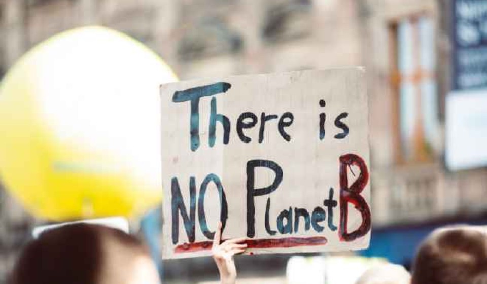 A hand holds a placard that reads "There is NO planet B"