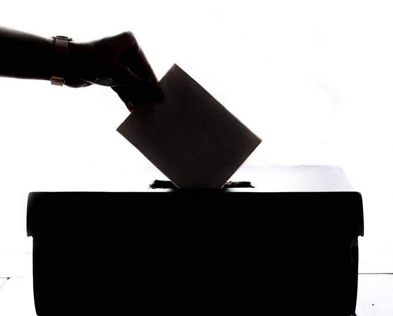 A silhouette of a person casting a vote