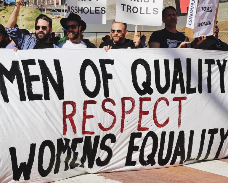 Hombres con un cartel que dice: Hombres de calidad respetan la iguldad de las mujeres.