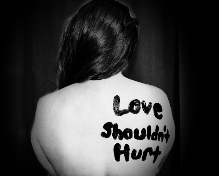 "Love shouldn't hurt" printed on back of a woman