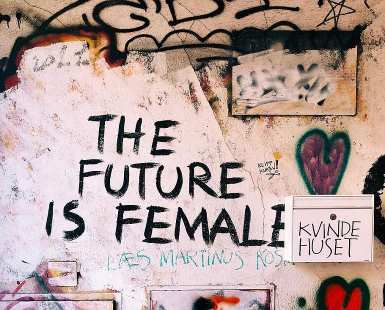 Quote on Graffiti-Covered Wall: "The Future is Female"
