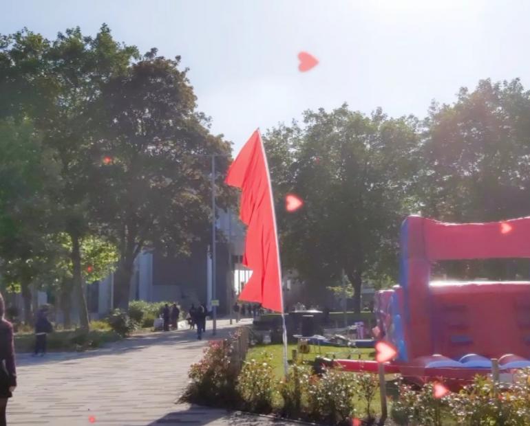 Image of a busy campus with trees, inflatables, colorful flags