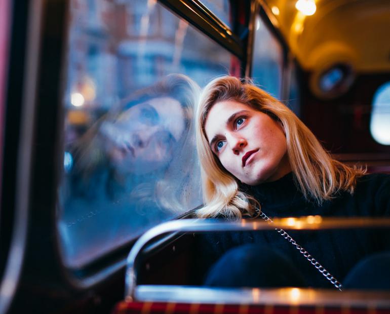 A woman leaning on a bus' window.