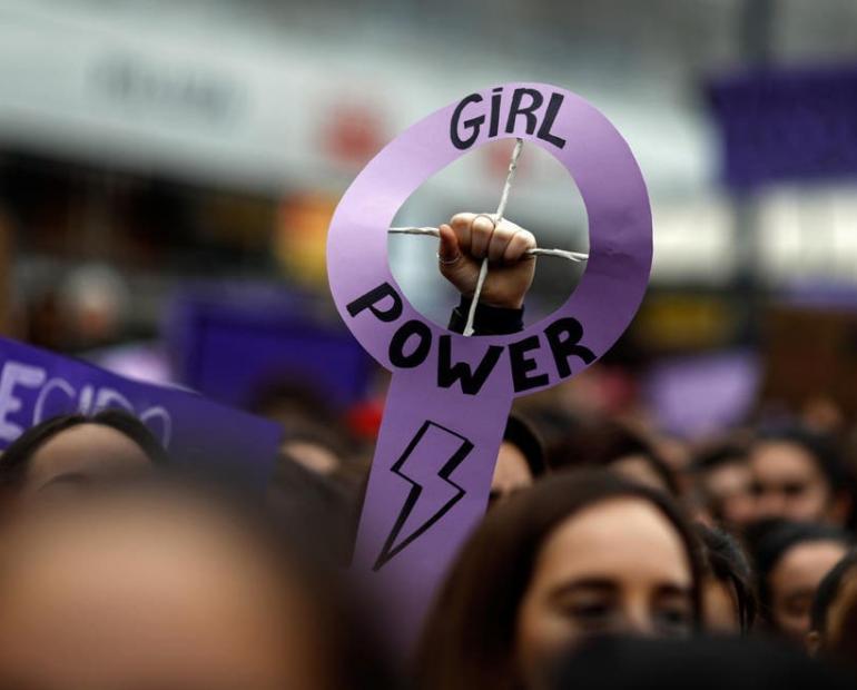 A women holding a purple sign that says girl power