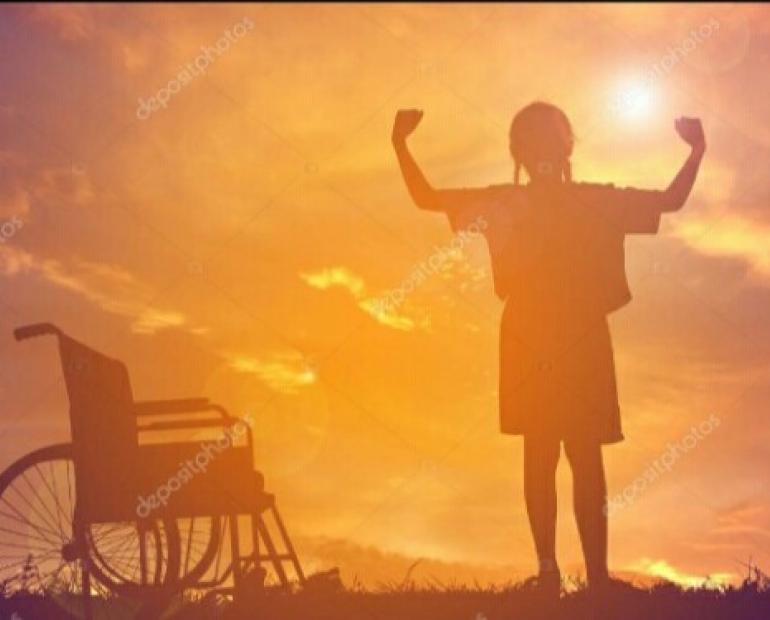 A girl standing by wheelchair during sunset