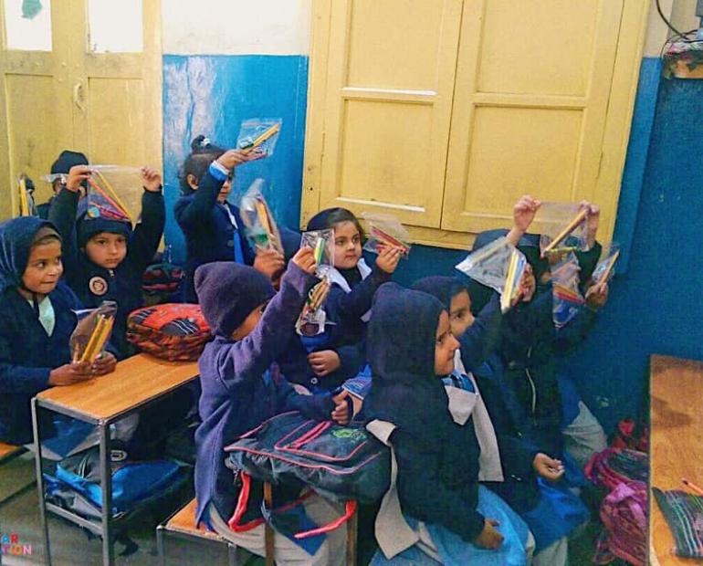 Students at a school in Pakistan holding up the school supply donations my non-profit, Aiza's Teddybear Foundation provided each class.