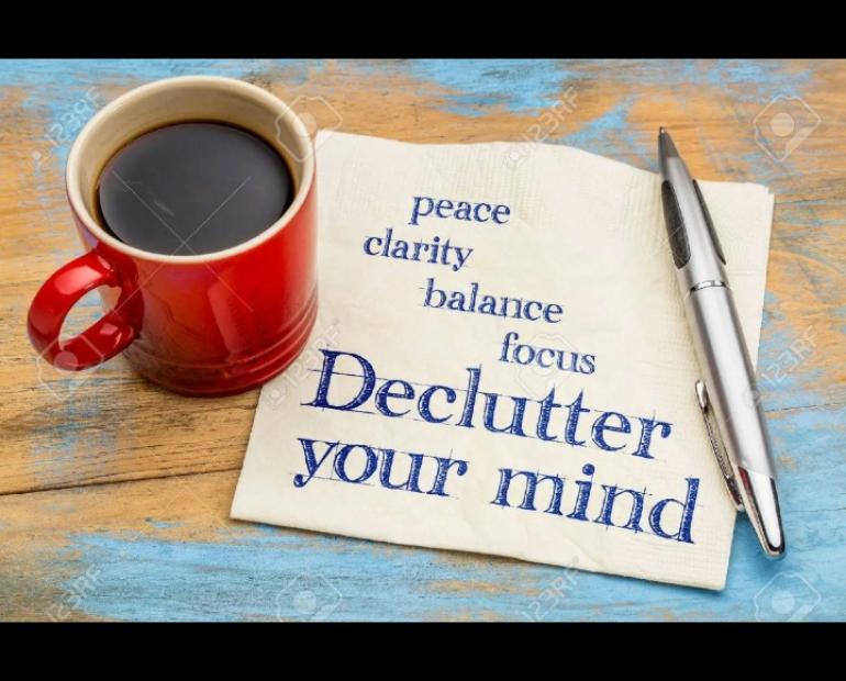 A paper on a table top with a pen and mug full of tea. Peace, clarity, balance, focus, declutter your mind is written on the paper.