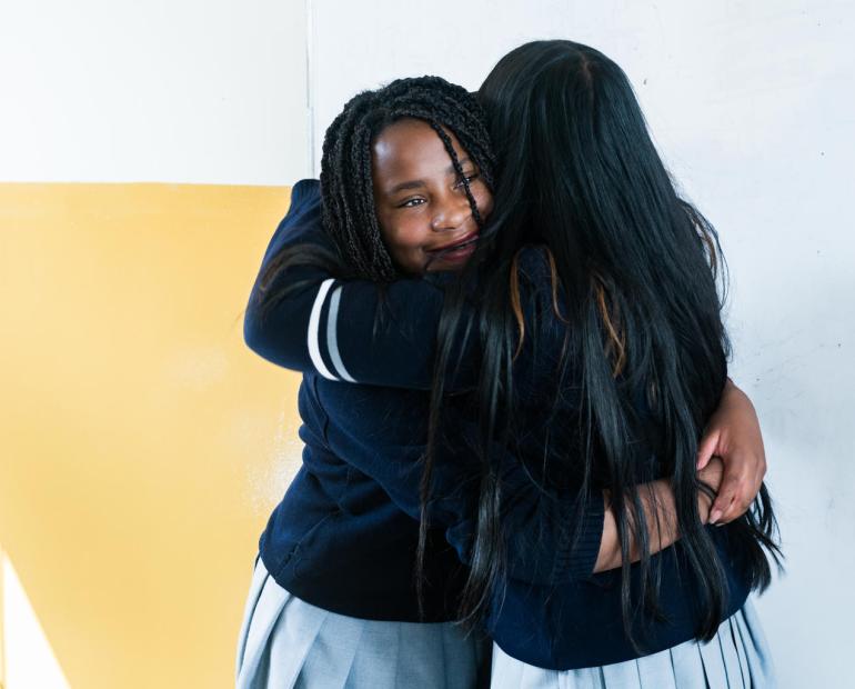 Two students from a school in Ecuador share a hug after taking part in a kindness activation.