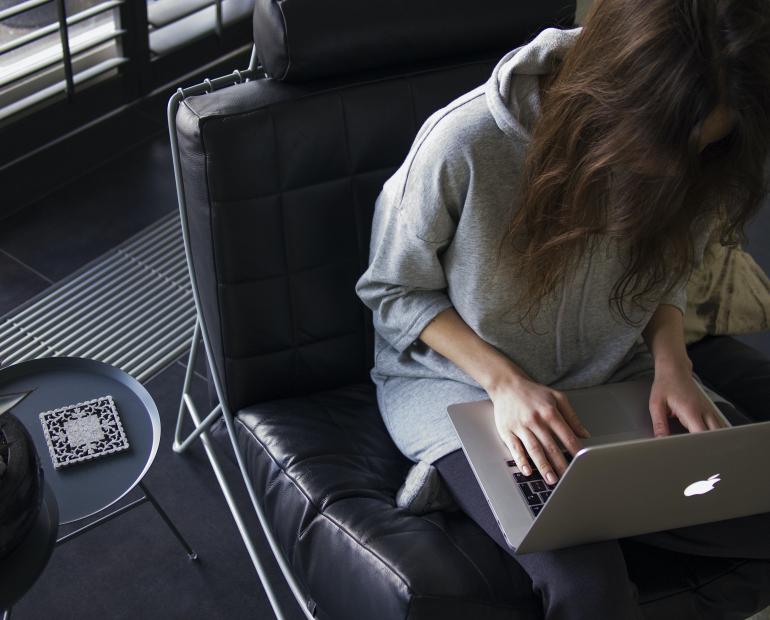 Woman sitting in a chair working on her laptop.