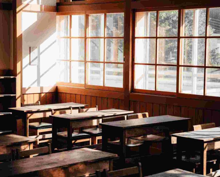 A classroom with empty desks and light coming in through the windows.