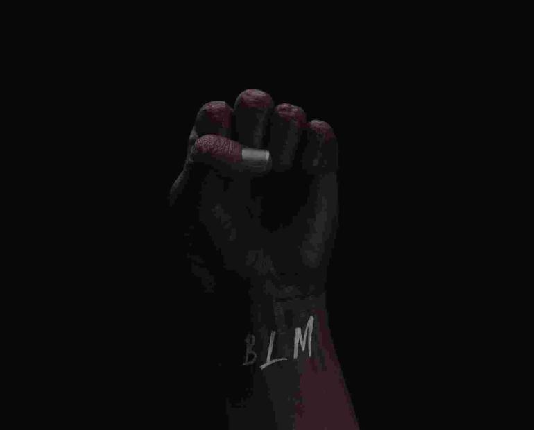 A fist in the air, the letters "BLM" written on the wrist.