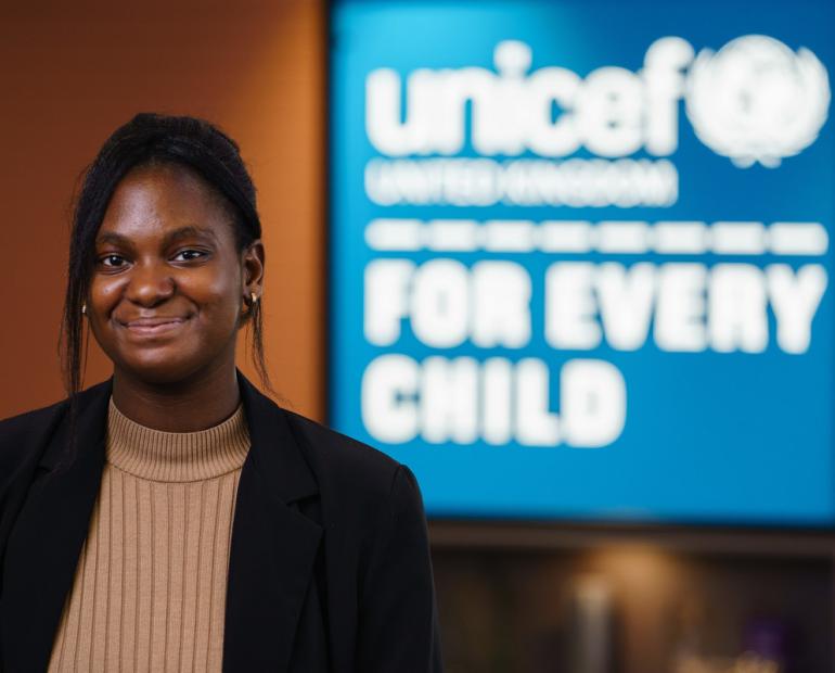 Sam poses for a picture in front of a UNICEF banner.