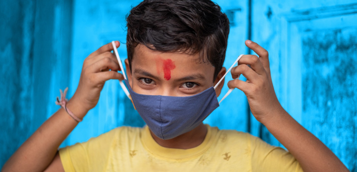 A boy in India teaches of how properly use a mask.
