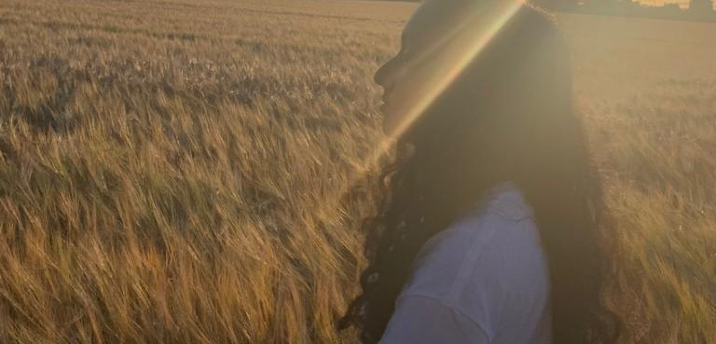 A girl walking on a field with a golden sunset. 