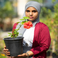 Fatima holds a pot with a flower.