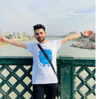 Mujtaba poses with his arms open, a river in the background.