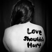 "Love shouldn't hurt" printed on back of a woman