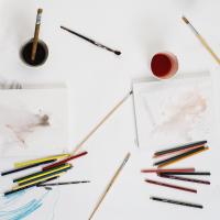 Different art supplies on a white workspace.