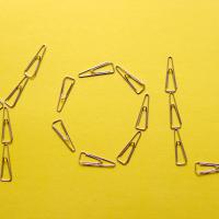 Paper clips position to spell out "You" on a yellow paper.
