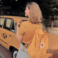 Chica de cabello rubio con una mochila amarilla y un auto delante de ella de color amarillo.