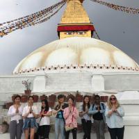 Students visiting the boudhanath temple pose with teachers in the "Namaste" position.