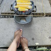 Sitting patiently by a hot brazier roasting corn.