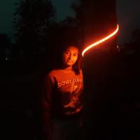 Ankitha Shreya Prasad standing near coconut tree at night her face is illuminating as she is facing towards LED lights